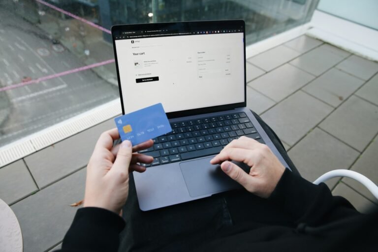 A person holding a payment card while using a computer