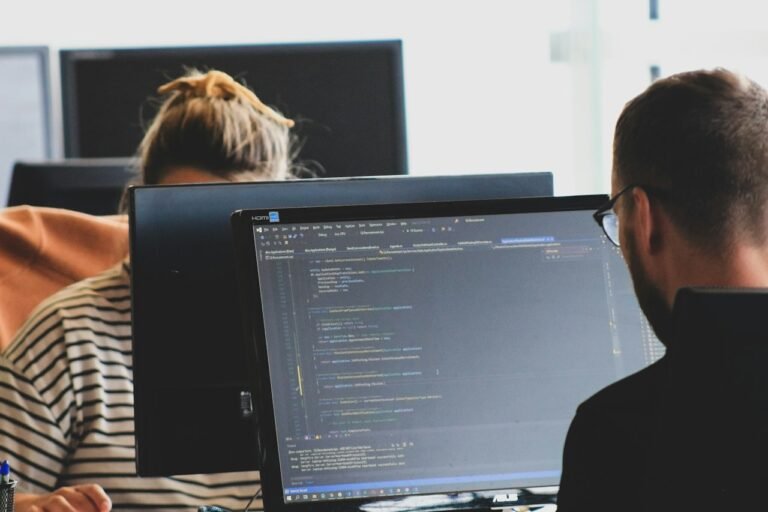 Two people working at computer monitors in an office
