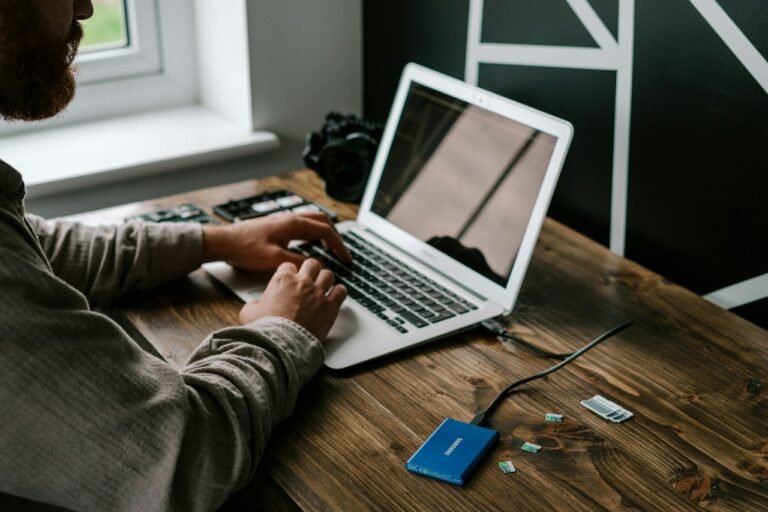 A person working on a laptop at a wooden table